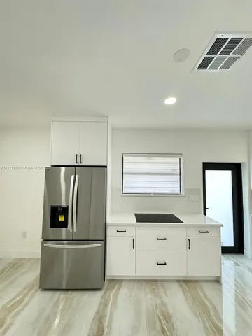 a kitchen with stainless steel appliances kitchen island sink refrigerator and cabinets