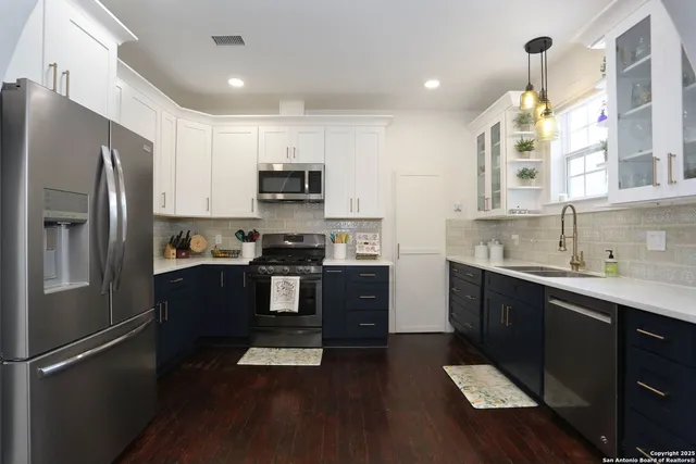a kitchen with a refrigerator a sink dishwasher and a stove top oven with wooden floor