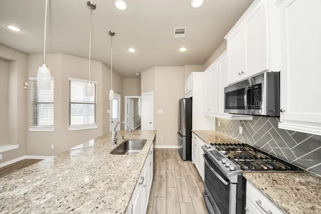 a kitchen with stainless steel appliances kitchen island granite countertop a stove and a sink