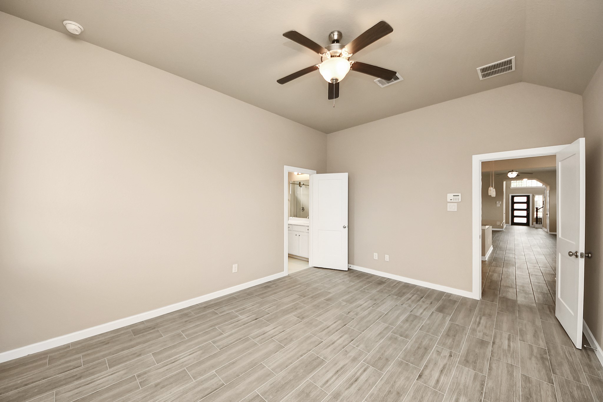 6030 Rivercane Way Katy, TX 77493 - Photo 21 of 41 The primary bedroom offers high ceiling with wood-like tile and blinds. Just through the door on the left, is the en suite and spacious walk-in closet. Primary bedroom located around the corner from the kitchen.