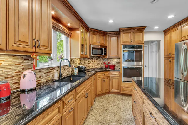 a kitchen with kitchen island granite countertop a sink appliances cabinets and furniture