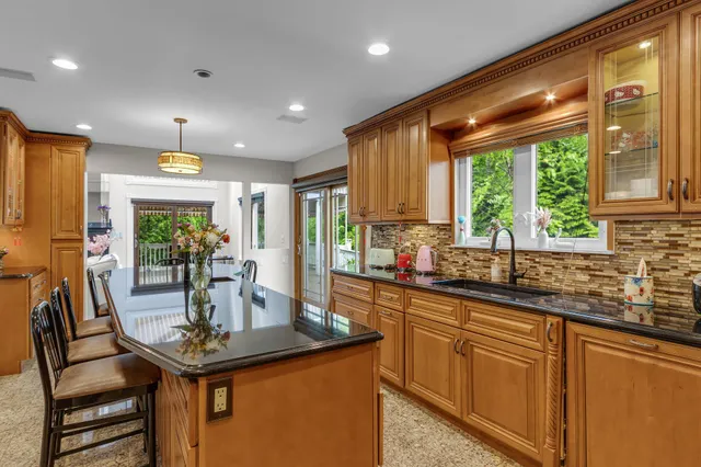 a kitchen with kitchen island a large window cabinets a sink and stainless steel appliances