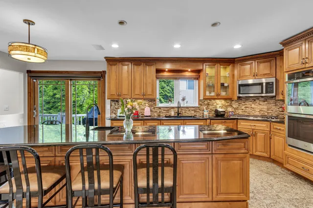 a kitchen with stainless steel appliances granite countertop a stove a sink dishwasher and a microwave oven with large wooden cabinets