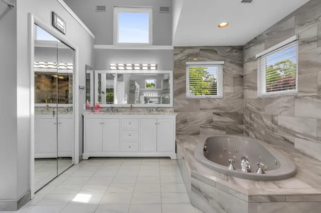 a spacious bathroom with a granite countertop sink a mirror and bathtub
