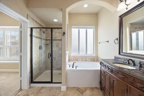 a bathroom with a granite countertop tub sink shower and mirror