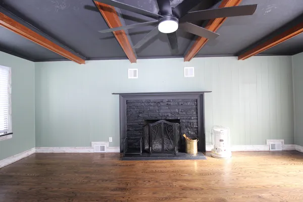 a view of an empty room with wooden floor and a fireplace