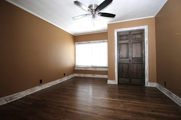 an empty room with wooden floor closet and windows