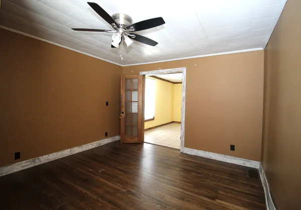 an empty room with wooden floor ceiling fan and windows
