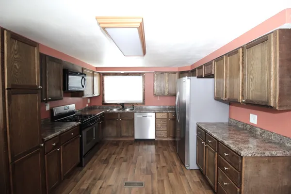 a kitchen with a refrigerator a stove top oven and wooden floor