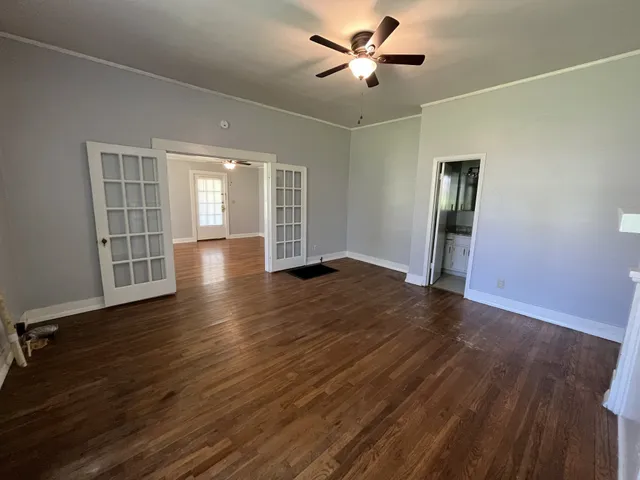an empty room with wooden floor chandelier fan and windows
