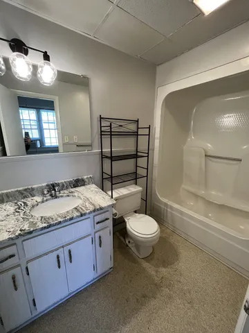 a bathroom with a granite countertop toilet sink and mirror