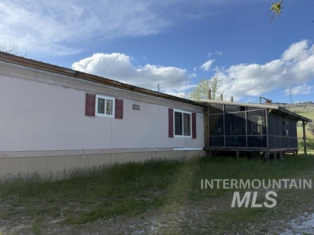 140 Brownlee Loop Road Horseshoe Bend, ID 83629 - Photo 18 of 29 Exterior featuring beige siding, red shutters, and an enclosed screened porch
