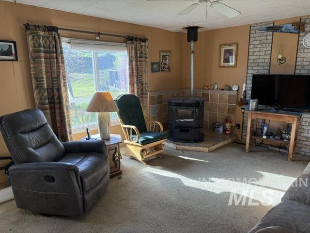 140 Brownlee Loop Road Horseshoe Bend, ID 83629 - Photo 19 of 29 Living space featuring a freestanding wood stove with a tiled hearth, an accent wall with a brick-finish panel, and a ceiling fan