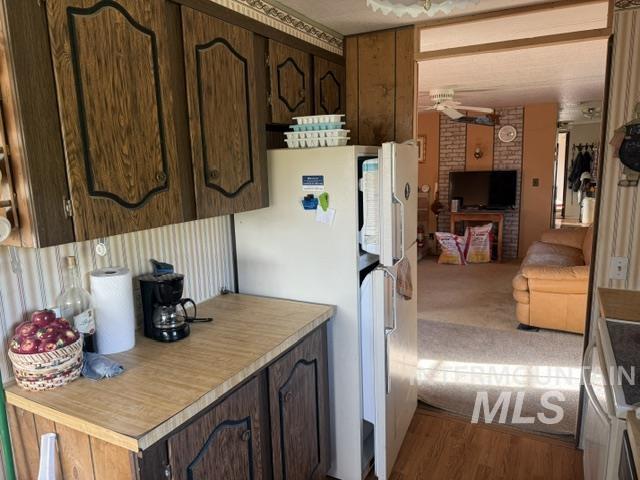 140 Brownlee Loop Road Horseshoe Bend, ID 83629 - Photo 21 of 29 Kitchen featuring wood-look cabinetry with decorative black trim, light wood-look countertops, and vertical striped wallpaper