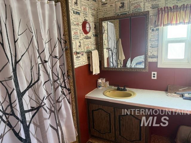 140 Brownlee Loop Road Horseshoe Bend, ID 83629 - Photo 26 of 29 Bathroom featuring a vanity with a yellow sink, a wall-mounted mirror with an ornate frame, a window with a striped valance, and a paneled lower wall