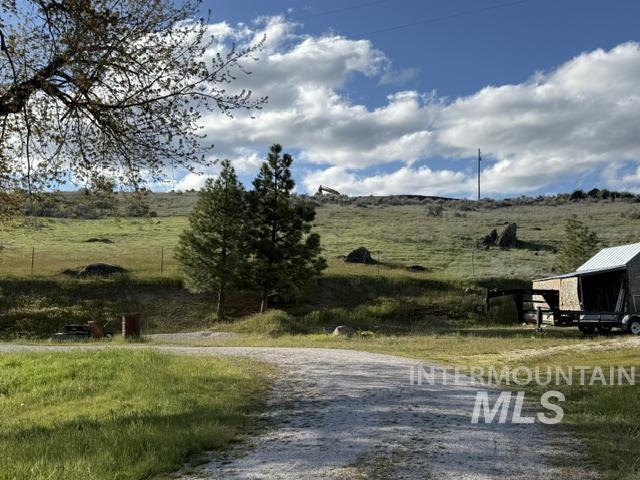 140 Brownlee Loop Road Horseshoe Bend, ID 83629 - Photo 4 of 29 Gravel driveway accessing a sloped, grassy terrain with scattered trees and natural rock formations