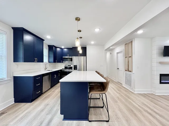 a kitchen with stainless steel appliances kitchen island granite countertop a table chairs in it and wooden floors