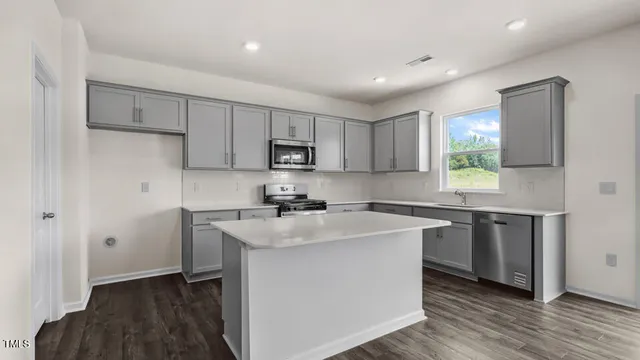 a kitchen with kitchen island a sink dishwasher a stove and white refrigerator with wooden floor