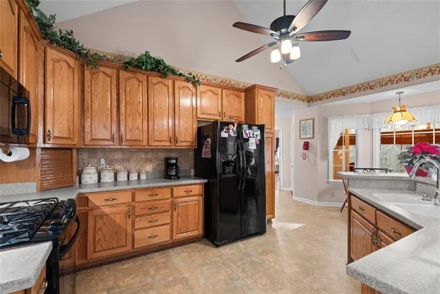 a kitchen with stainless steel appliances kitchen island granite countertop a stove a refrigerator a sink a dining table and chairs with wooden floor