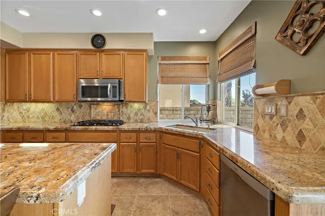 a kitchen with stainless steel appliances granite countertop a stove a sink and a microwave