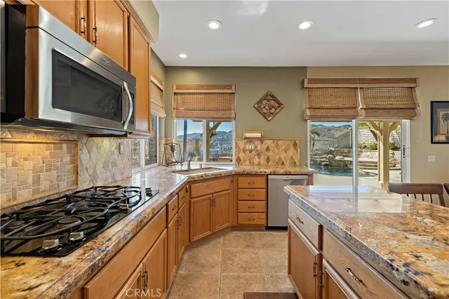 a open kitchen with stainless steel appliances granite countertop a stove top oven a sink dishwasher and couches with wooden floor