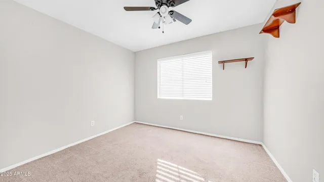 an empty room with a window and a ceiling fan