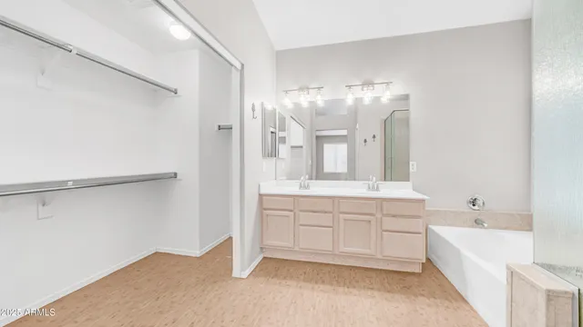 a spacious bathroom with a double vanity sink a mirror and a bathtub