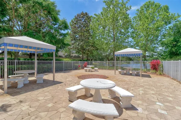 a view of a patio with a dining table and chairs under an umbrella with large trees