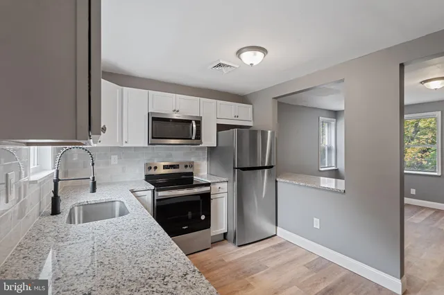 a kitchen with granite countertop a refrigerator stove and sink