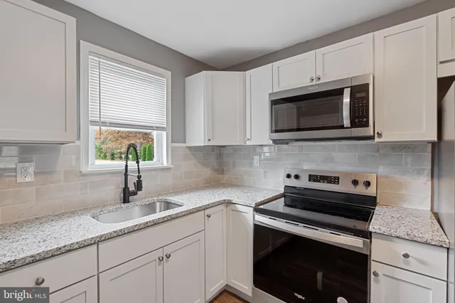 a kitchen with granite countertop cabinets stainless steel appliances a sink and window