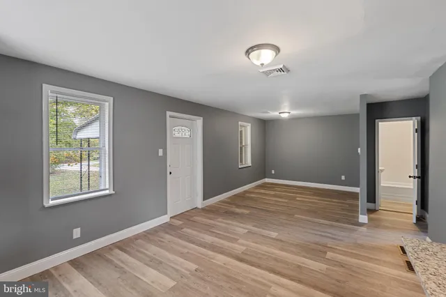 a view of an empty room with wooden floor and a window