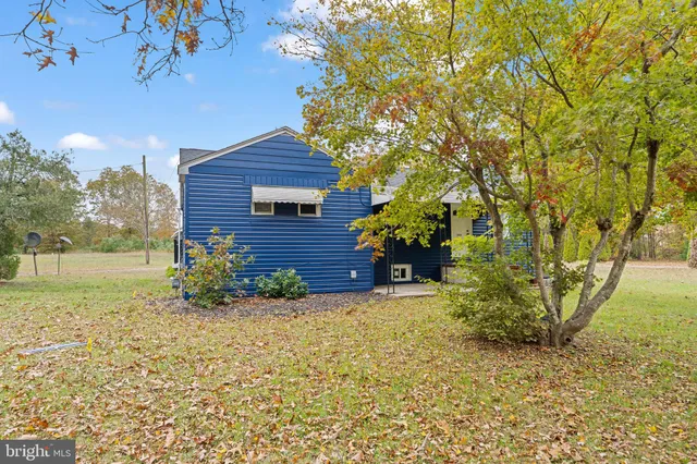 a yellow house with a yard and trees in front of it