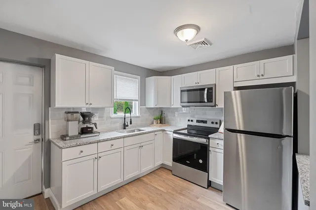a kitchen with a sink white cabinets and stainless steel appliances