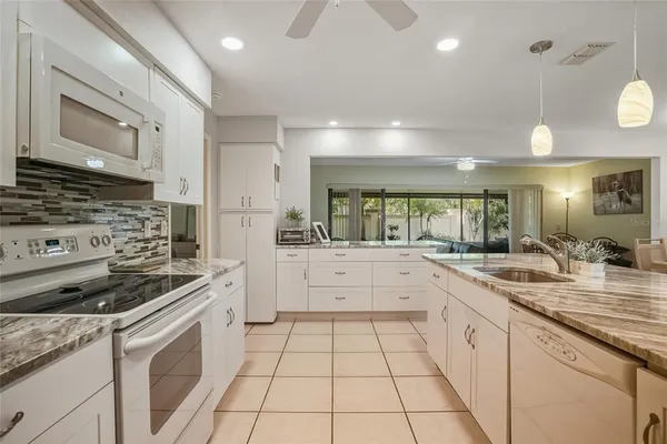 a kitchen with a sink dishwasher stove and white cabinets with wooden floor