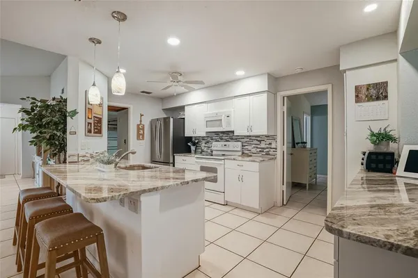 a kitchen with kitchen island granite countertop lots of white cabinets and stainless steel appliances
