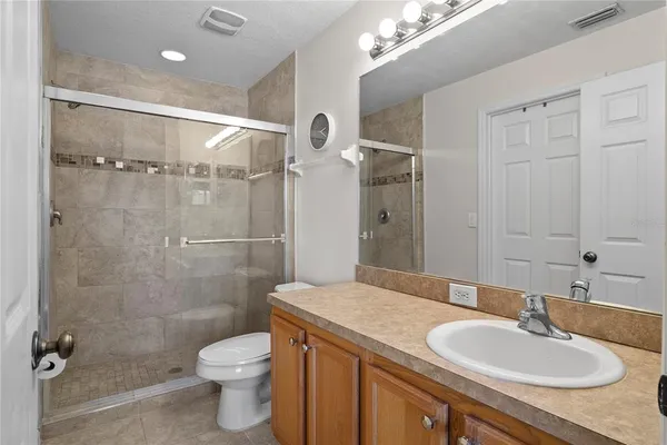 a bathroom with a granite countertop sink toilet a mirror and shower