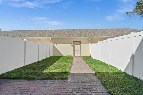 a view of a backyard with lawn chairs under an umbrella