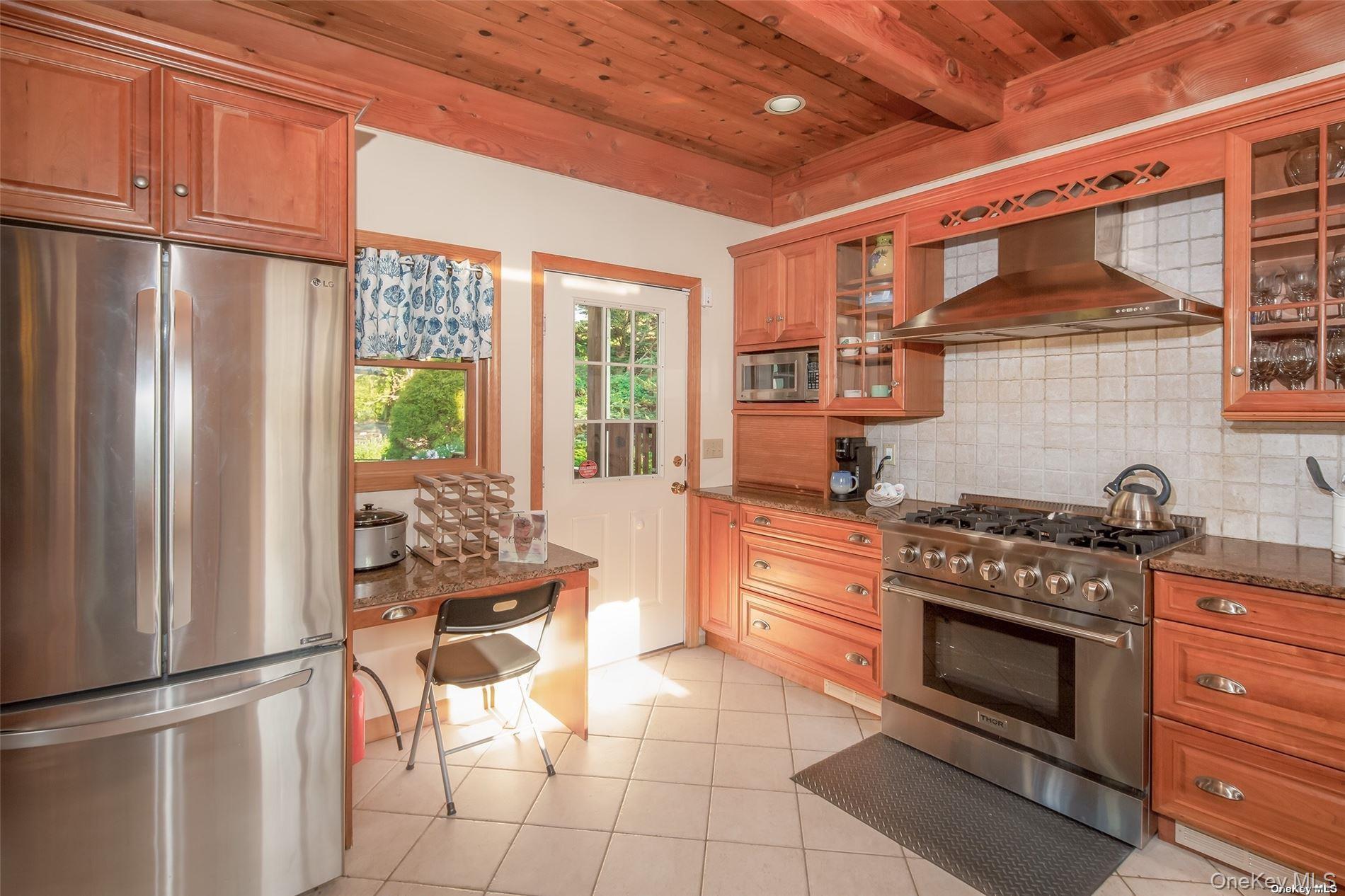 48 Oakhurst Road Hampton Bays, NY 11946 - Photo 12 of 25 a kitchen with stainless steel appliances granite countertop a stove and a refrigerator