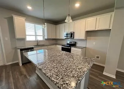 a kitchen with stainless steel appliances kitchen island granite countertop a sink stove and white cabinets