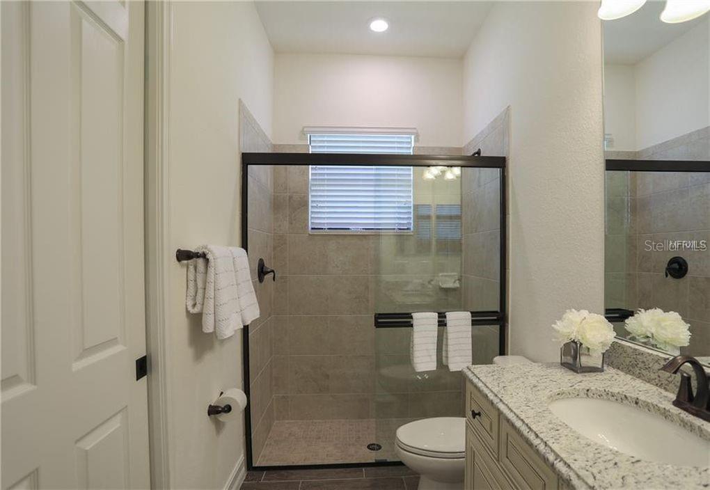5528 Arnie Loop Lakewood Ranch, FL 34211 - Photo 29 of 59 a bathroom with a granite countertop sink toilet and shower
