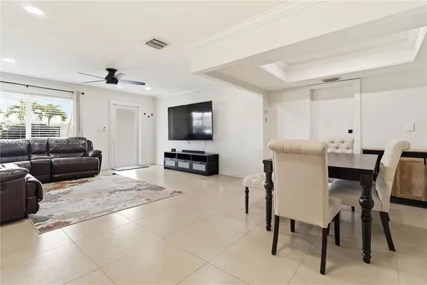 a living room with furniture a flat screen tv and kitchen view
