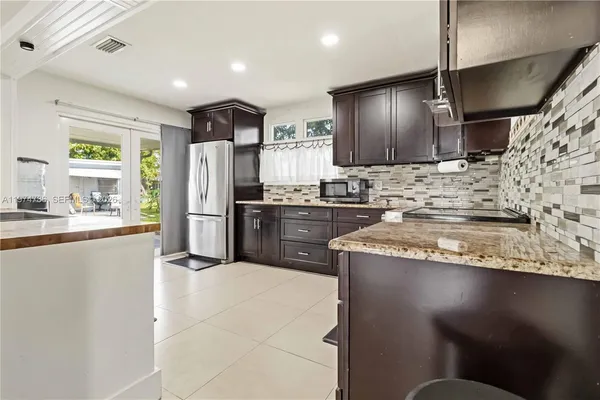 a kitchen with stainless steel appliances granite countertop a sink a stove and a refrigerator
