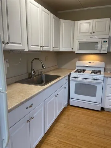 a kitchen with granite countertop white cabinets and white appliances