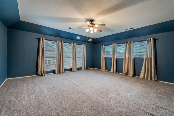 an empty room with chandelier fan and windows