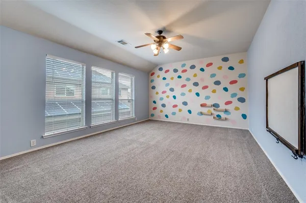 a view of an empty room with window and chandelier fan