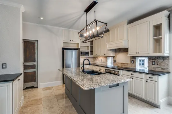 a kitchen with granite countertop stainless steel appliances a sink a stove and cabinets