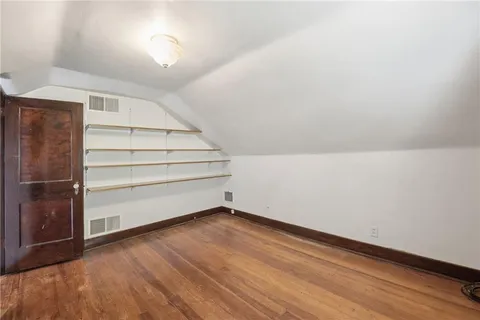 a view of an empty room with wooden floor and white walls