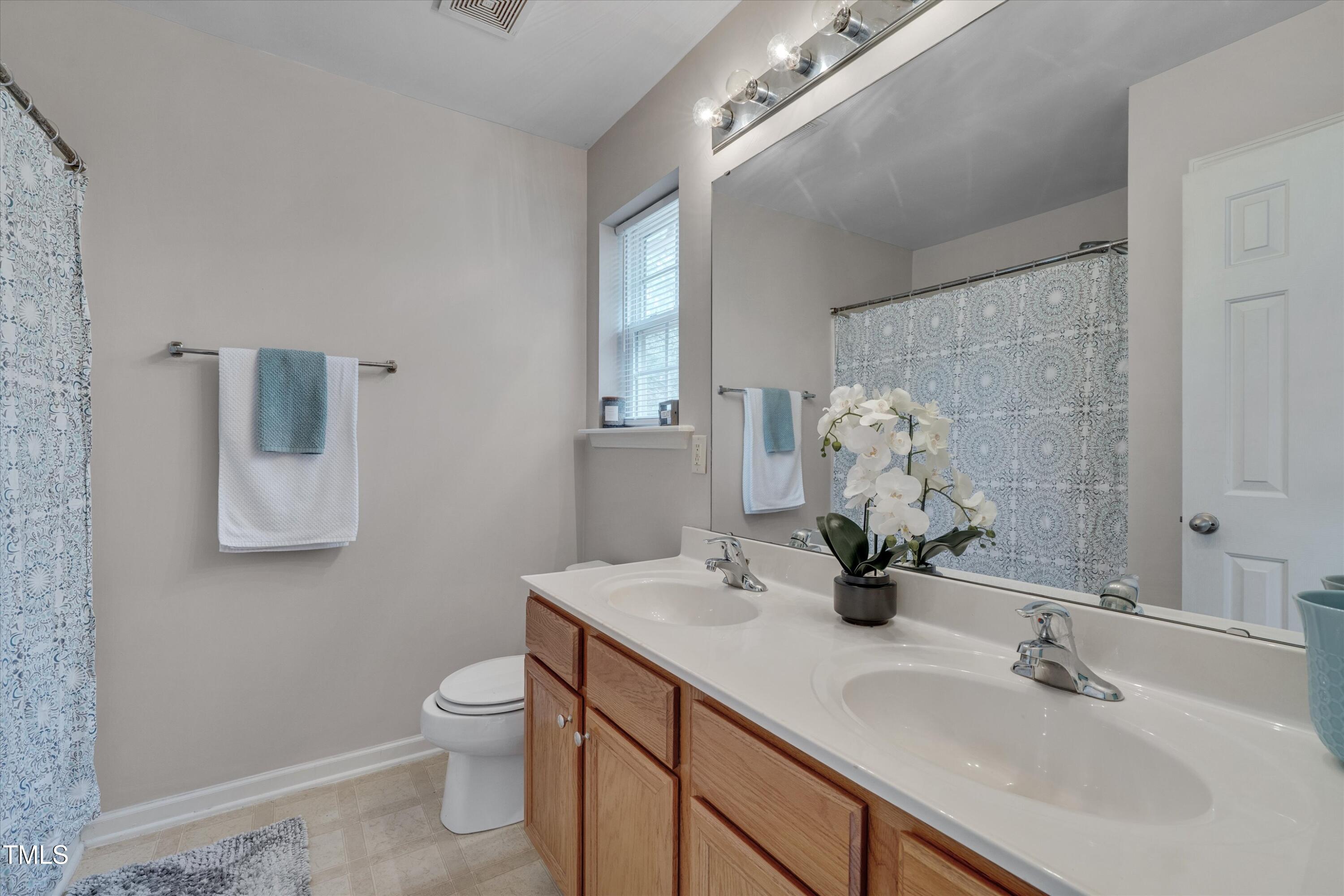 7704 Averette Field Drive Raleigh, NC 27616 - Photo 16 of 25 a bathroom with a double vanity sink toilet and a mirror