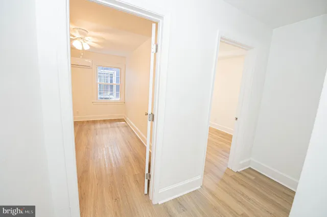 a view of a hallway with wooden floor and a bathroom