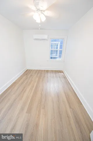 an empty room with wooden floor chandelier fan and windows